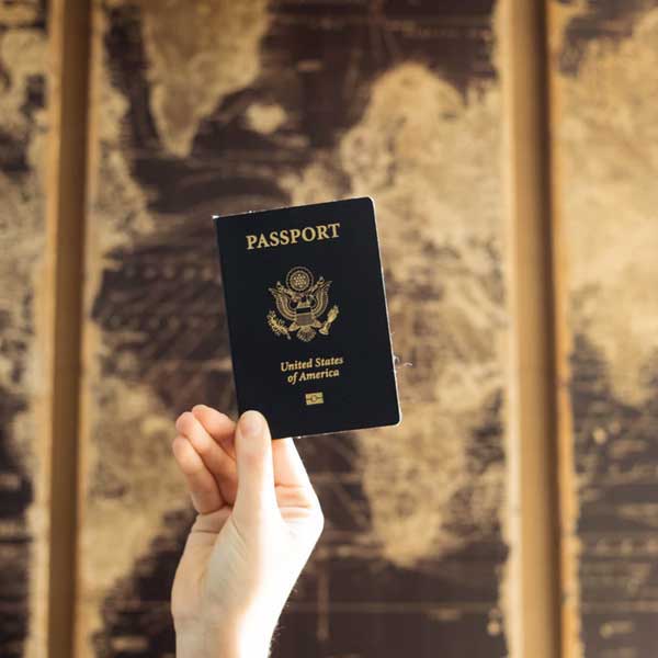 Hand holding a passport with a map in the background